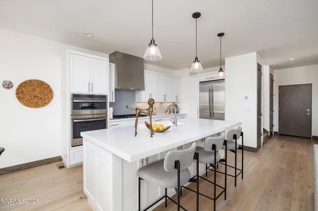 a kitchen with stainless steel appliances granite countertop a sink a stove a refrigerator and island with wooden floor