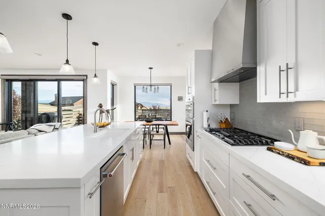 a kitchen with stainless steel appliances granite countertop a stove a sink and white cabinets with wooden floor