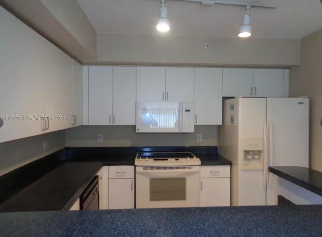 a kitchen with a refrigerator and white cabinets