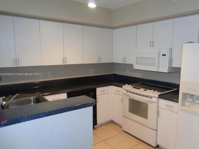 a kitchen with granite countertop white cabinets and white appliances