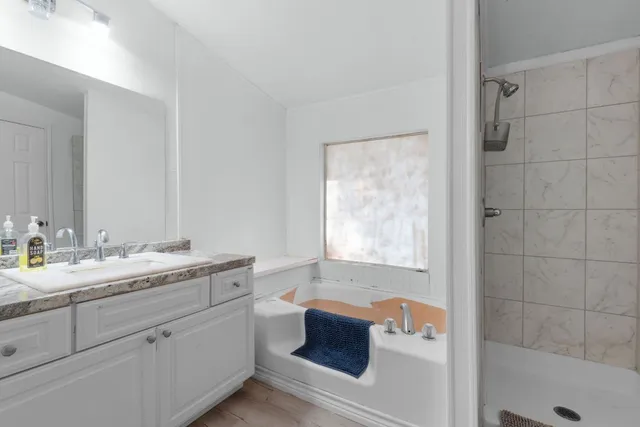 a bathroom with a granite countertop sink mirror and bathtub