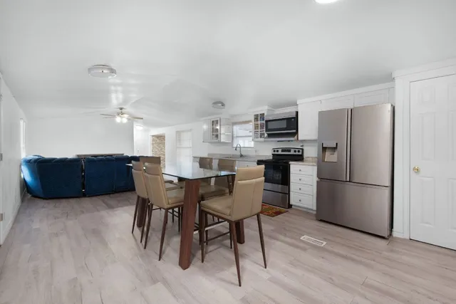 a kitchen with stainless steel appliances a refrigerator a stove a sink dishwasher and a dining table with wooden floor