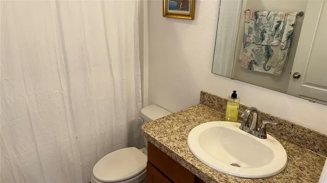 a bathroom with a granite countertop toilet sink and mirror