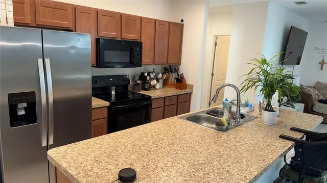 a kitchen with stainless steel appliances kitchen island granite countertop a refrigerator a stove and a sink