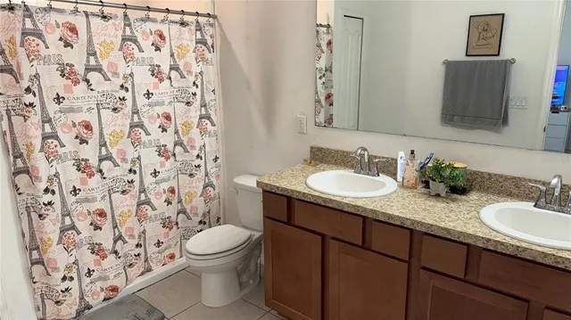 a bathroom with a granite countertop sink toilet a mirror and shower curtain