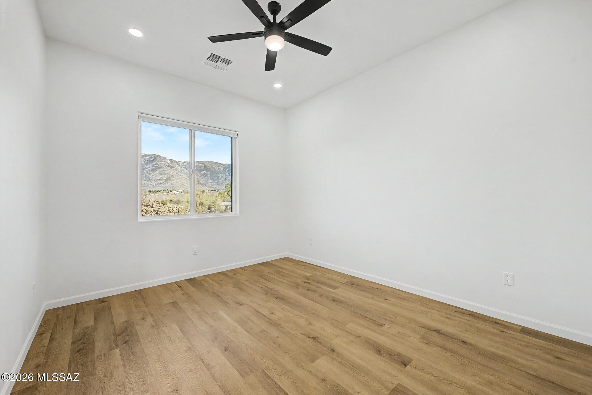 4601 East Magoo Road Tucson, AZ 85739 - Photo 16 of 38 an empty room with a ceiling fan and wooden floor
