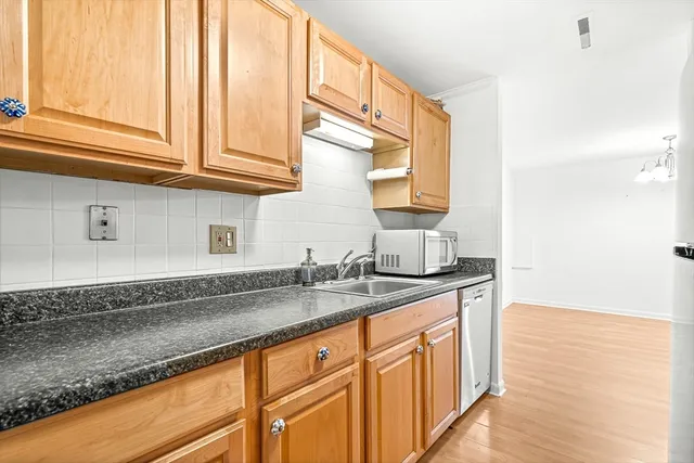 a kitchen with stainless steel appliances granite countertop a sink and dishwasher with wooden floor