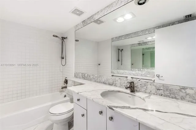 a bathroom with a granite countertop sink toilet mirror and bathtub