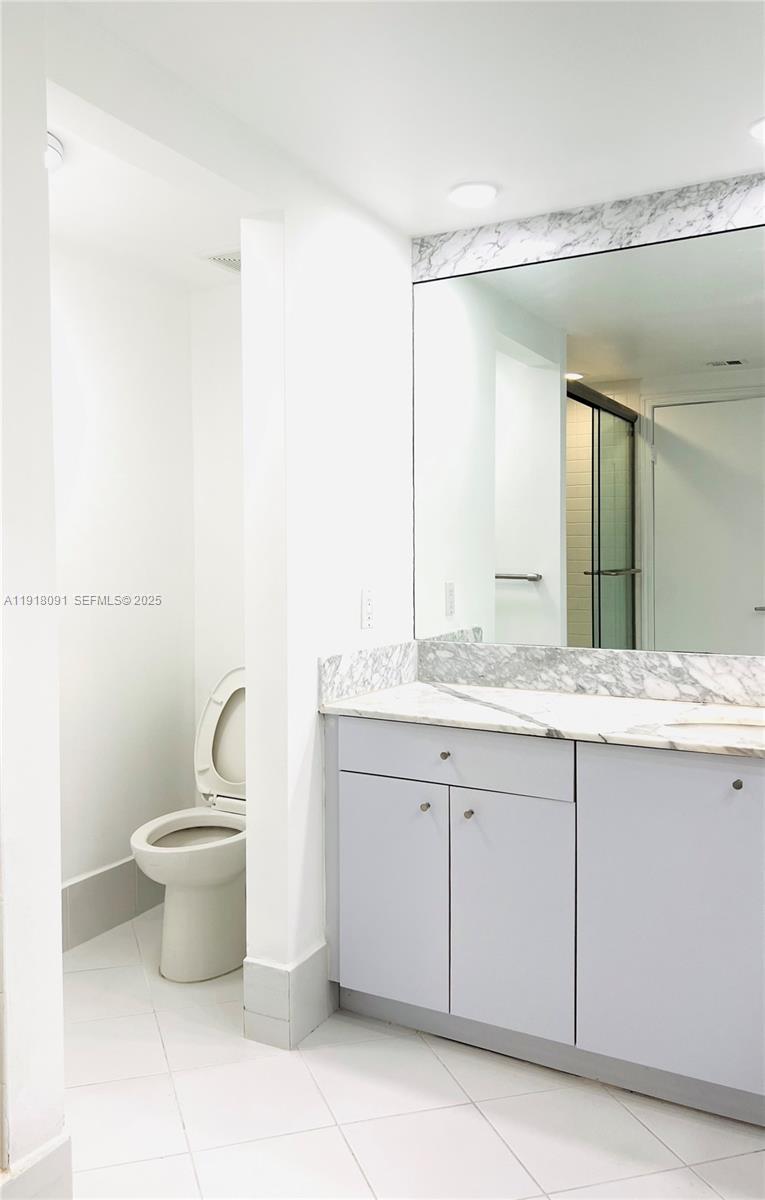 1 Grove Isle Drive, Unit A405 Miami, FL 33133 - Photo 7 of 21 a bathroom with a granite countertop sink a toilet and a mirror