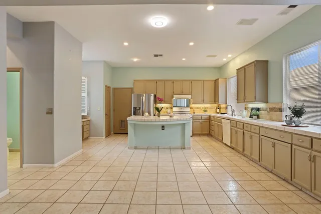 a kitchen with kitchen island cabinets a sink a counter and a refrigerator