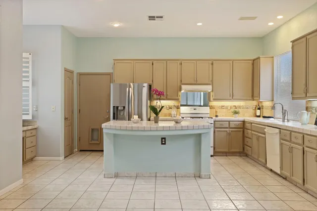 a kitchen with kitchen island granite countertop a sink refrigerator and cabinets