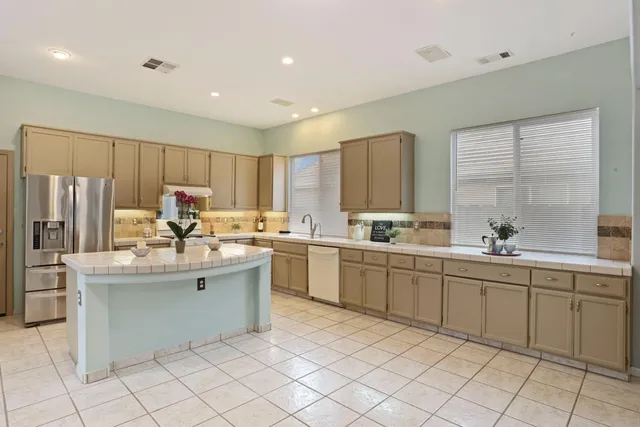 a view of a kitchen with kitchen island a sink wooden floor and a large window