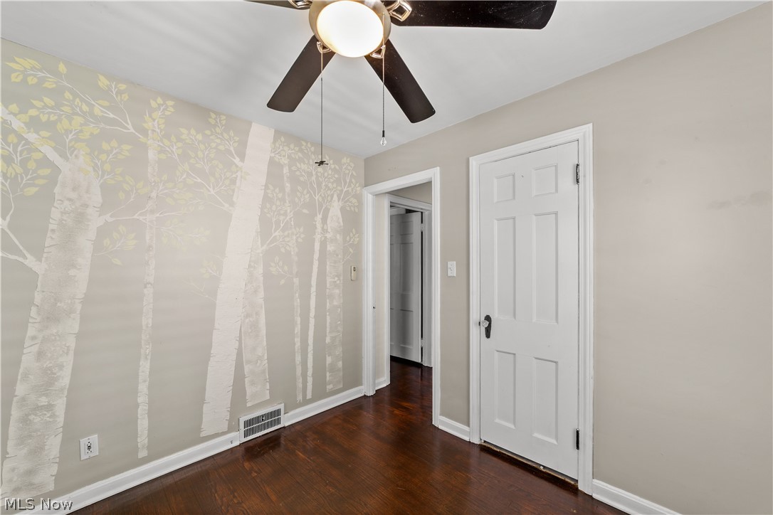 3806 Westwood Road University Heights, OH 44118 - Photo 23 of 41 Bedroom with painted accent wall featuring tree motifs, dark wood-finish flooring, white baseboards, and a ceiling fan with integrated lighting