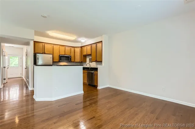 a kitchen with stainless steel appliances granite countertop a stove top oven a sink and dishwasher with wooden floor