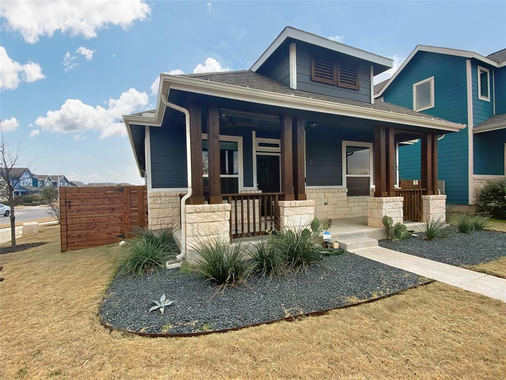 8901 Panhandle Drive Austin, TX 78747 - Photo 2 of 21 Contemporary exterior featuring dark blue siding, light stone veneer accents, a covered front porch with exposed wood columns, a prominent dormer, and a wood privacy fence