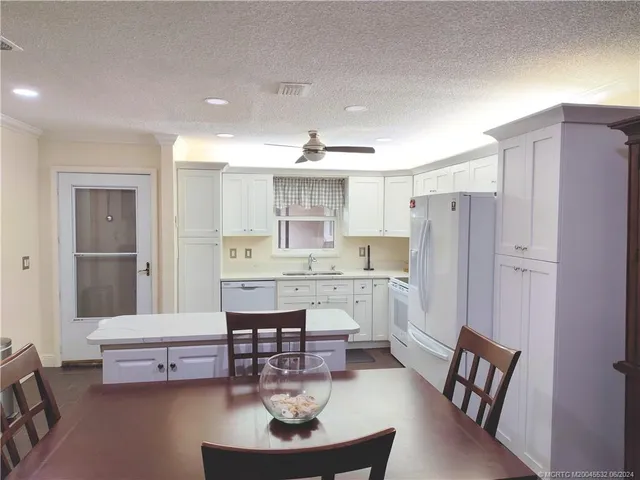 a kitchen with a sink dishwasher a dining table and chairs with wooden floor