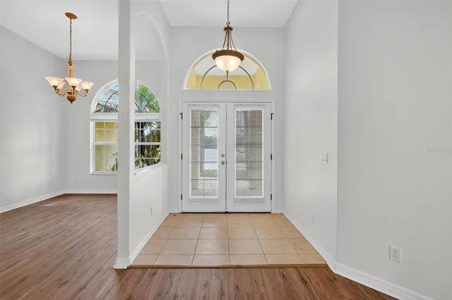 a view of a room with wooden floor chandelier and windows