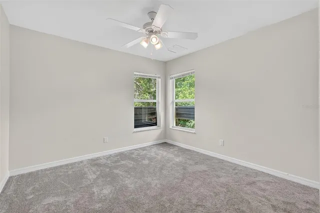 an empty room with windows and chandelier fan