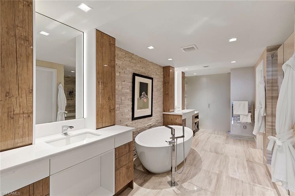 6897 Grenadier Boulevard, Unit 902 Naples, FL 34108 - Photo 27 of 50 a bathroom with a double vanity sink a mirror and a toilet