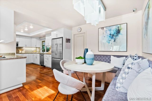 a kitchen with stainless steel appliances kitchen island granite countertop a dining table chairs and a refrigerator