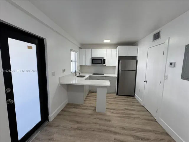 a kitchen with refrigerator cabinets and wooden floor