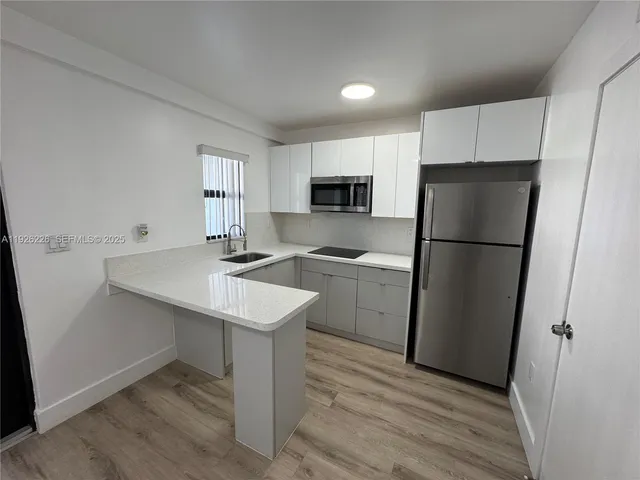 a kitchen with a sink a refrigerator and a stove top oven