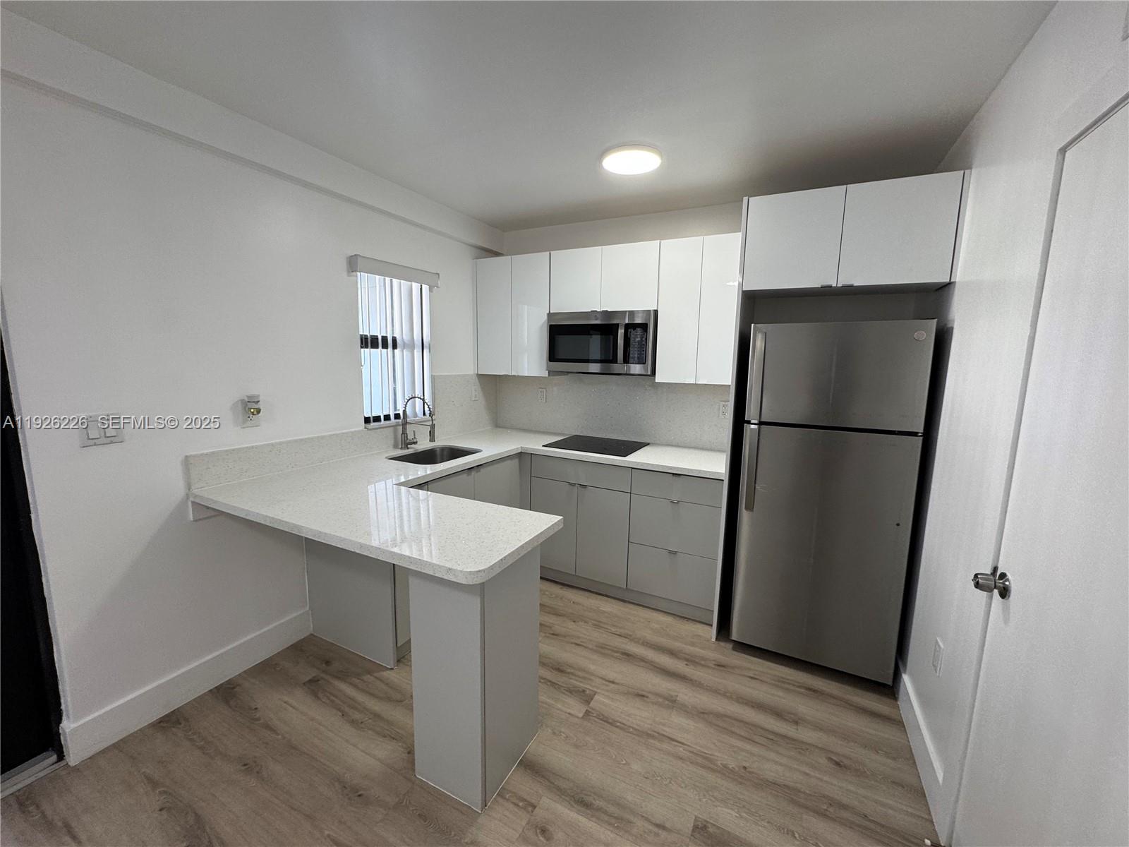 1969 Northwest 2nd Court, Unit 6 Miami, FL 33136 - Photo 4 of 17 a kitchen with a sink a refrigerator and a stove top oven