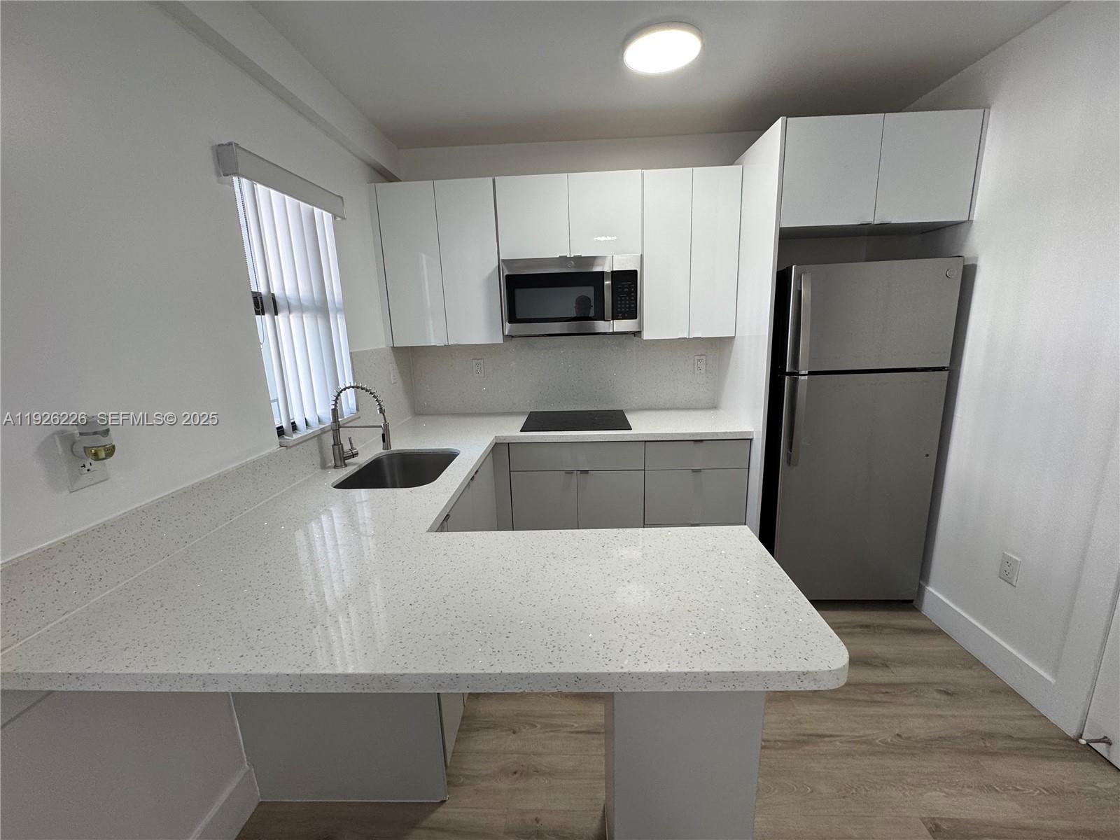 1969 Northwest 2nd Court, Unit 6 Miami, FL 33136 - Photo 5 of 17 a kitchen with a refrigerator a sink a stove a microwave and cabinets