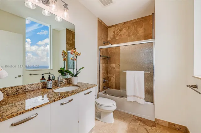 a bathroom with a granite countertop sink toilet and shower