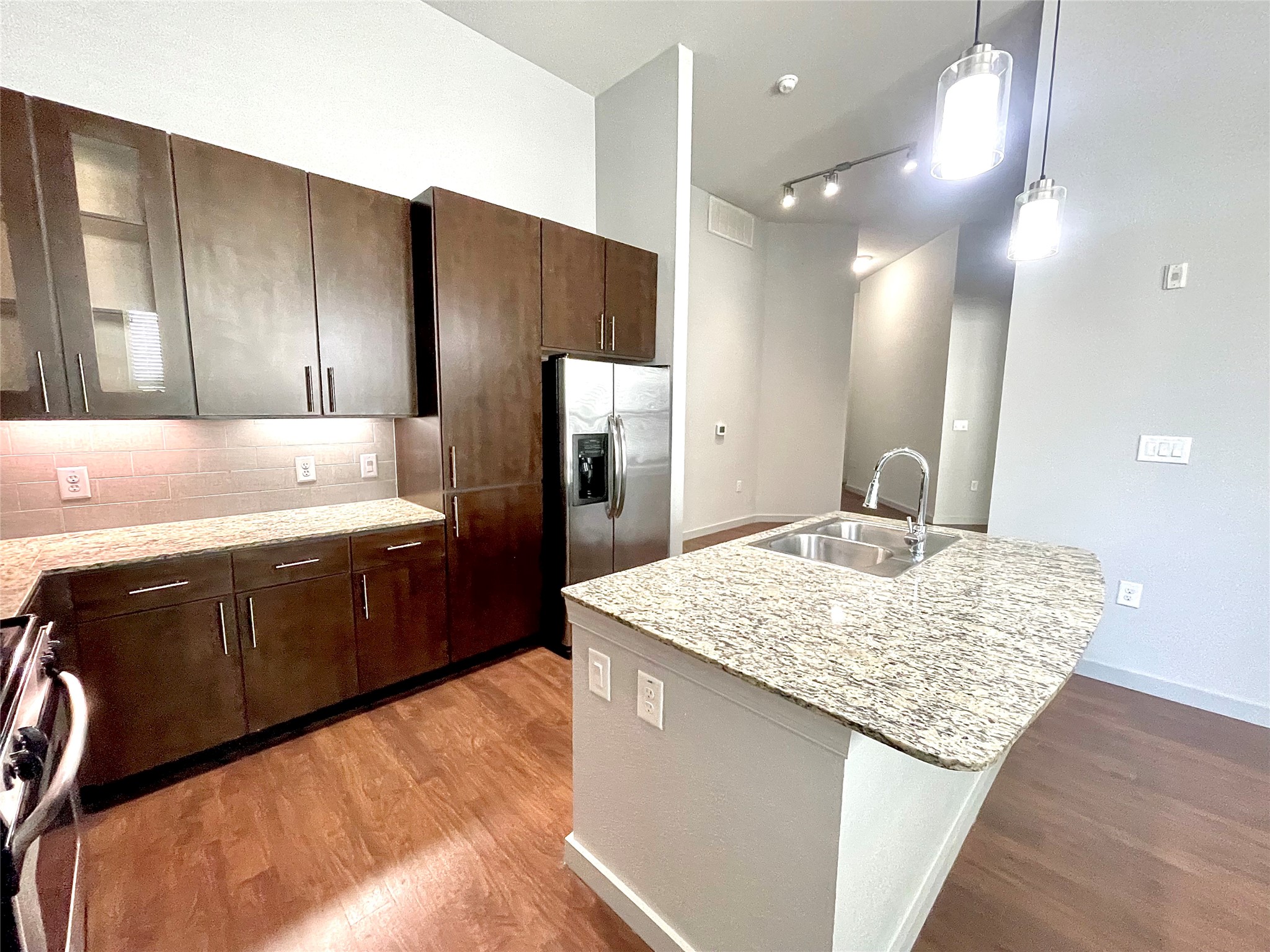 2525 McCue Road, Unit 327 Houston, TX 77056 - Photo 2 of 9 a kitchen with stainless steel appliances kitchen island granite countertop wooden cabinets a granite counter tops and a view of living room