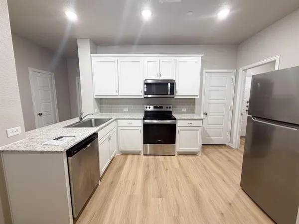a kitchen with a sink a refrigerator a microwave and cabinets