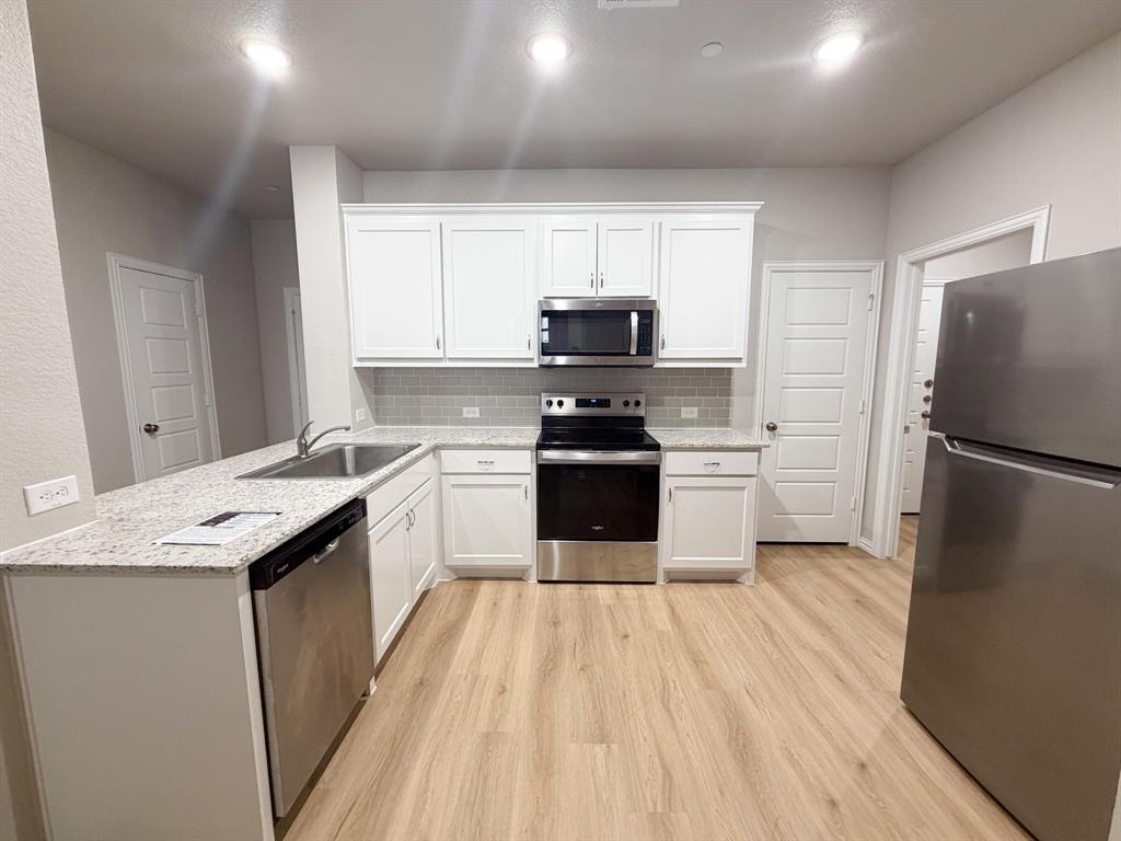 432 Restoration Road Waxahachie, TX 75165 - Photo 7 of 20 a kitchen with a sink a refrigerator a microwave and cabinets