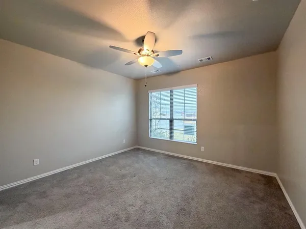 an empty room with windows and fan