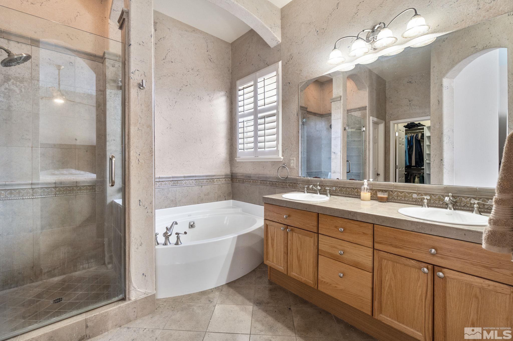 9607 Glen Ridge Drive Reno, NV 89521 - Photo 15 of 22 a bathroom with a tub a double vanity sink and a mirror