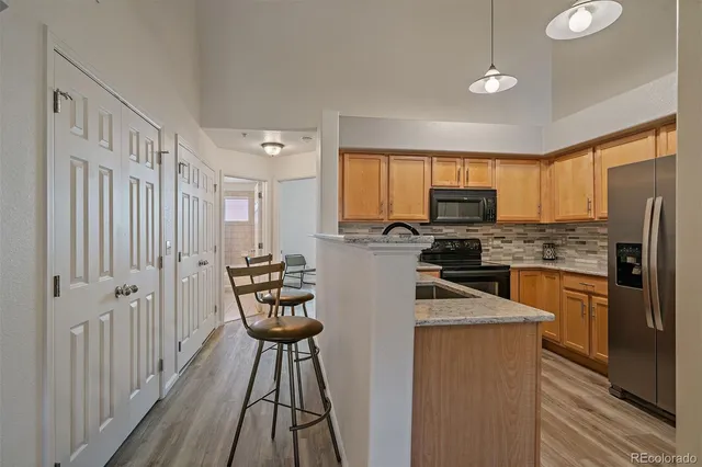 a kitchen with stainless steel appliances granite countertop a refrigerator a stove top oven a sink dishwasher and white cabinets with wooden floor
