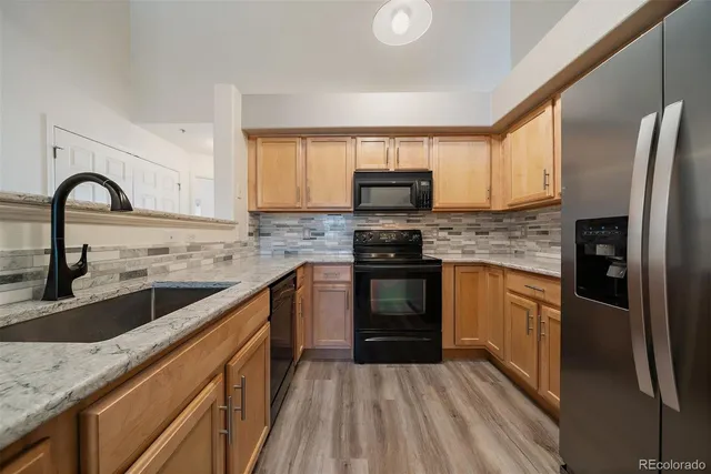 a kitchen with stainless steel appliances granite countertop a refrigerator a sink and wooden cabinets