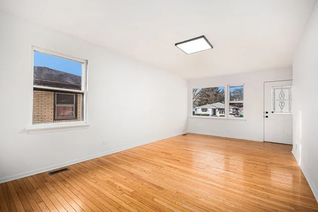 a view of empty room with wooden floor and window