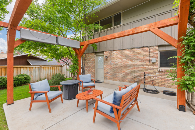 3320 Cherokee Lane Provo, UT 84604 - Photo 44 of 52 Outdoor patio featuring a wooden pergola with integrated sunshades, a concrete surface, a brick exterior wall, and surrounding green landscaping