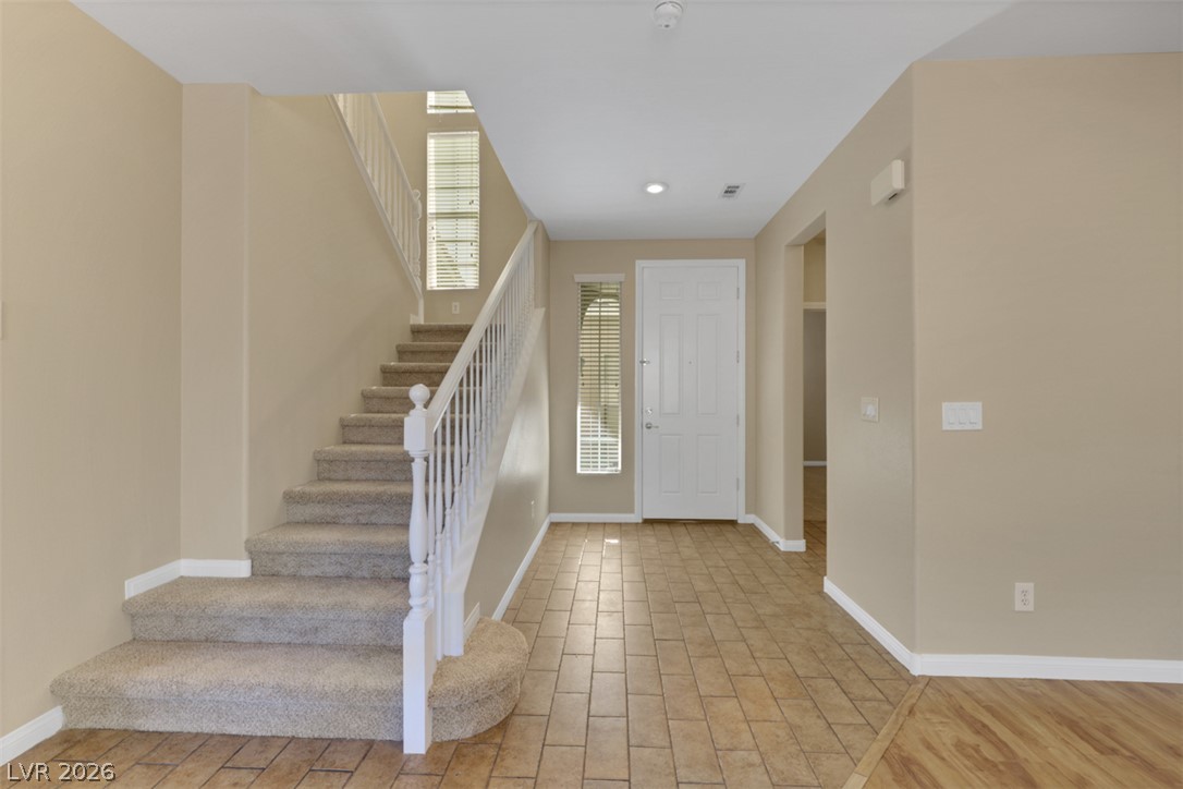 10328 Hawk Ravine Street Las Vegas, NV 89178 - Photo 5 of 55 A welcoming entryway with tile flooring leads to a carpeted staircase, creating a warm and functional transition.