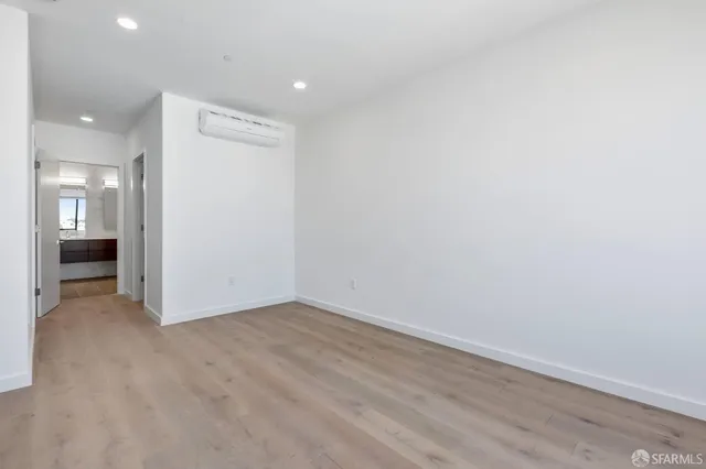 a view of an empty room with wooden floor and a kitchen