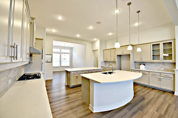 a kitchen with a stove a sink a refrigerator cabinets and wooden floor