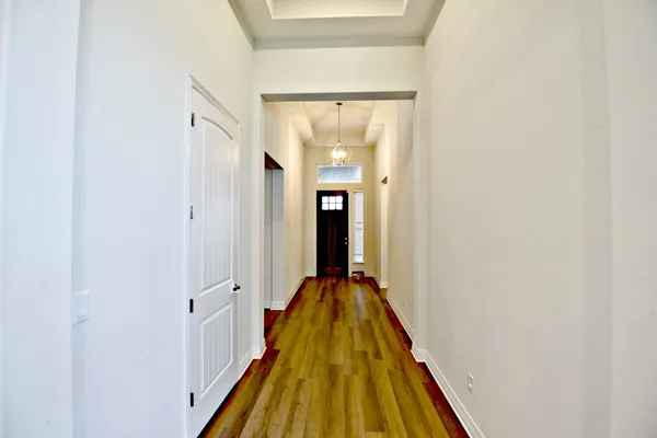 a view of a hallway with wooden floor and a bathroom
