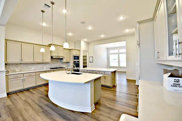 a large kitchen with kitchen island a stove a sink a center island and wooden floor