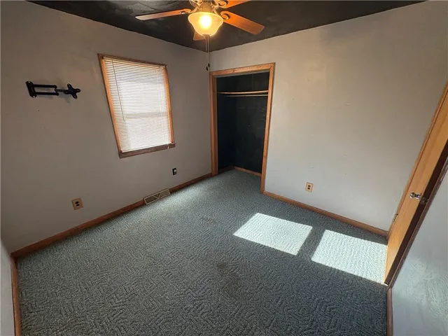 an empty room with a ceiling fan and windows