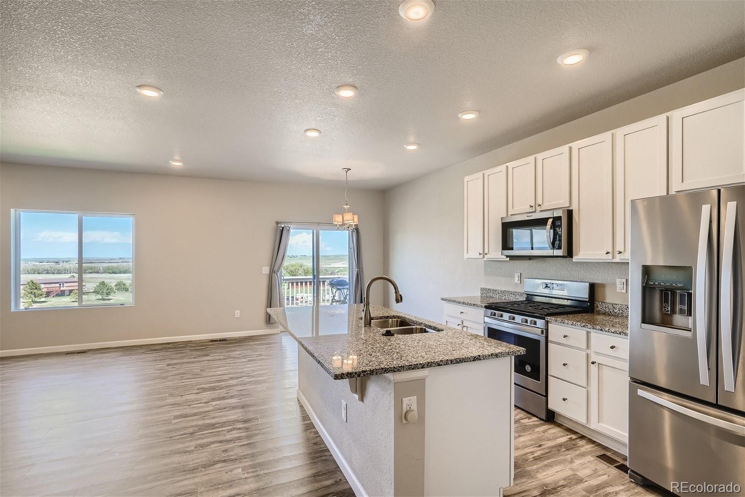 4718 River Highlands Loop Elizabeth, CO 80107 - Photo 12 of 28 a kitchen with stainless steel appliances granite countertop a stove a sink a refrigerator white cabinets and wooden floor