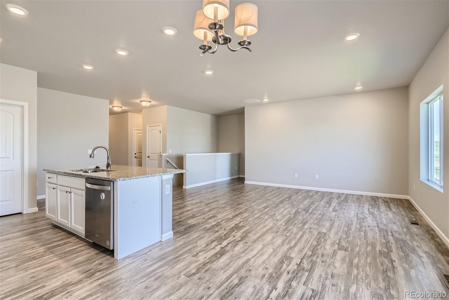 4718 River Highlands Loop Elizabeth, CO 80107 - Photo 14 of 28 a large kitchen with kitchen island a stove a sink wooden floor and a large window