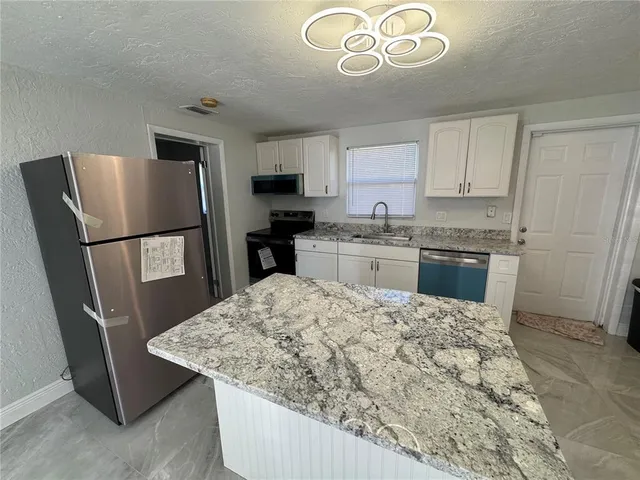a kitchen with stainless steel appliances granite countertop a refrigerator stove top oven a sink and dishwasher
