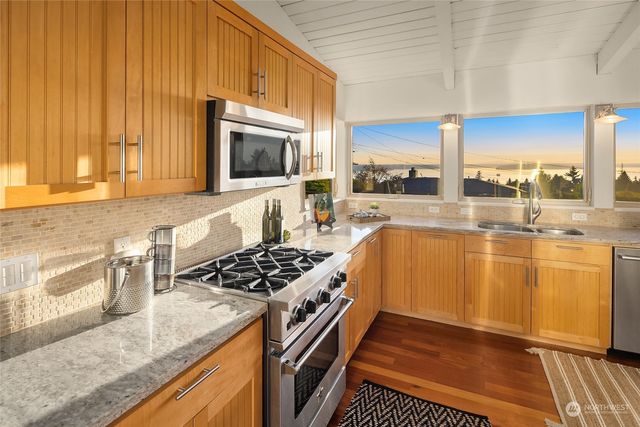 a kitchen with stainless steel appliances granite countertop a stove a sink and a microwave