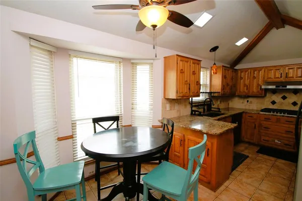 a kitchen with stainless steel appliances granite countertop a stove a sink dishwasher a dining table and chairs with wooden floor