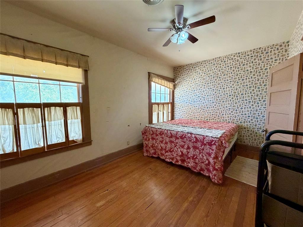 600 Mercer Street Quanah, TX 79252 - Photo 18 of 28 a bedroom with a bed next to a window with a chandelier